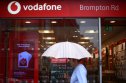 Vodafone in talks with Three vodafone shop in the rain with woman under umbrella