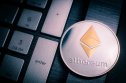 Silver Ethereum coin with gold Ethereum symbol on a laptop keyboard next to the Enter key