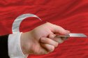 Turkey interest rate forecast for next 5 years man stretching out credit card to buy goods in front of complete wavy national flag of turkey