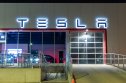 Tesla shareholders Tesla logo atop of a Tesla Dealership illuminated at night.