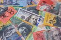 AUD/USD Aussie dollar A hundred US dollar bill from and colorful Australian dollars banknotes, symbolizing the AUD/USD exchange rate