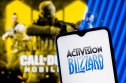 Activision Blizzard and Call of Duty Activision Blizzard logo on smartphone screen. A frame from the Call of Duty on the background.