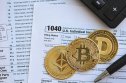Tax return document with coins with crypto logos on it. Tax return document with coins with crypto logos on it.