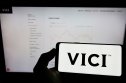 VICI Properties stock forecast Person holding cellphone with logo of US real estate company Vici Properties Inc. on screen in front of business webpage. Focus on phone display.