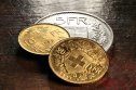 CHF Swiss gold and silver coins on rustic wooden background