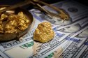 Gold nuggets in a bowl on US dollar bills