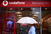 Vodafone in talks with Three vodafone shop in the rain with woman under umbrella