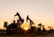 The silhouette of five oil pumps on a beautiful sunset sky with sun setting in between them The silhouette of five oil pumps on a beautiful sunset sky with sun setting in between them