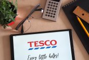 Tesco app on laptop next to calculator. Tesco app on laptop next to calculator.