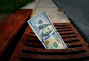US dollar extended losses US 100 Dollar banknote down the street storm drain