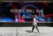 Pfizer share price A image of people in masks walking by the signs outside the Pfizer Building on 42nd street