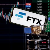 A smartphone in a shopping cart displays the FTX name and logo in front of a price chart
