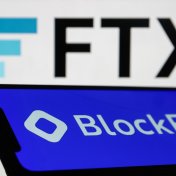 BlockFi name and logo displayed on a phone with the FTX logo behind on a laptop screen