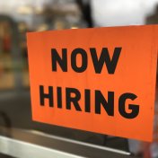 “now hiring” sign posted on business door