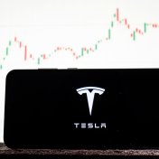 Tesla stock forecast 2022: Where next for the EV giant? Logo Tesla on a smartphone against the background of stock market trends. Tesla stock forecast 2022: Where next for the EV giant? Logo Tesla on a smartphone against the background of stock market trends.