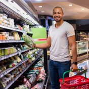 US retail sales Portrait of a smiling man holding spinach in a supermarket.