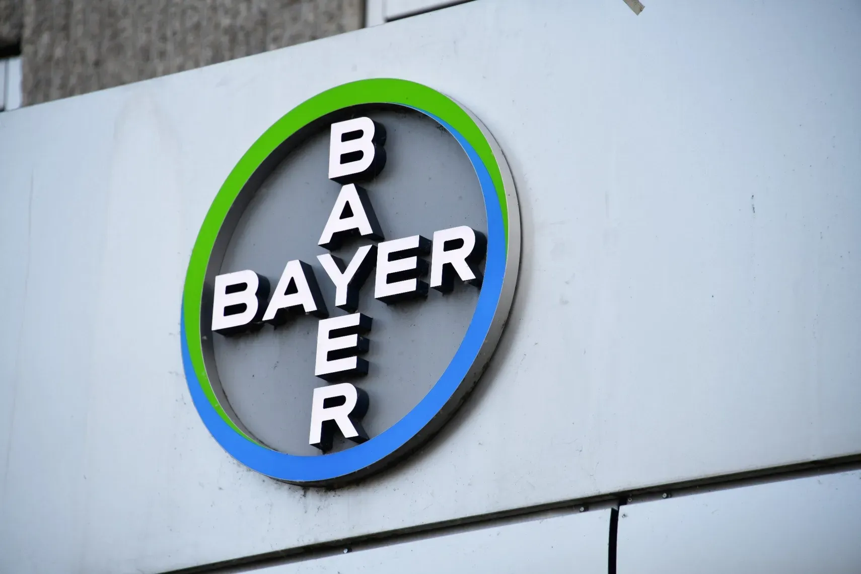 Bayer-Logo an der Außenwand eines Gebäudes mit kreisförmigem blau-grünem Design