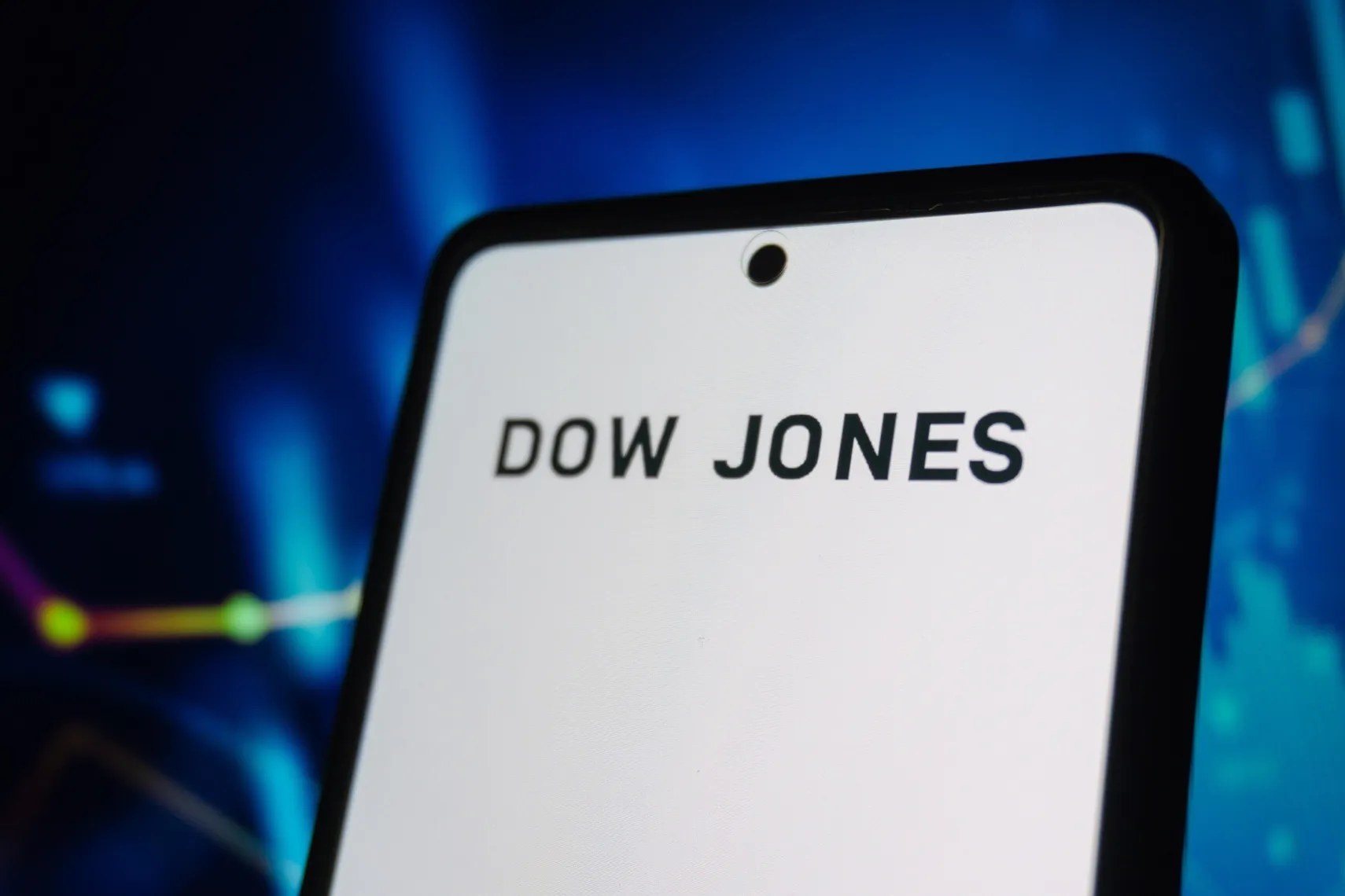 Smartphone displaying “Dow Jones” text with a blurred stock market chart in the background Smartphone displaying “Dow Jones” text with a blurred stock market chart in the background
