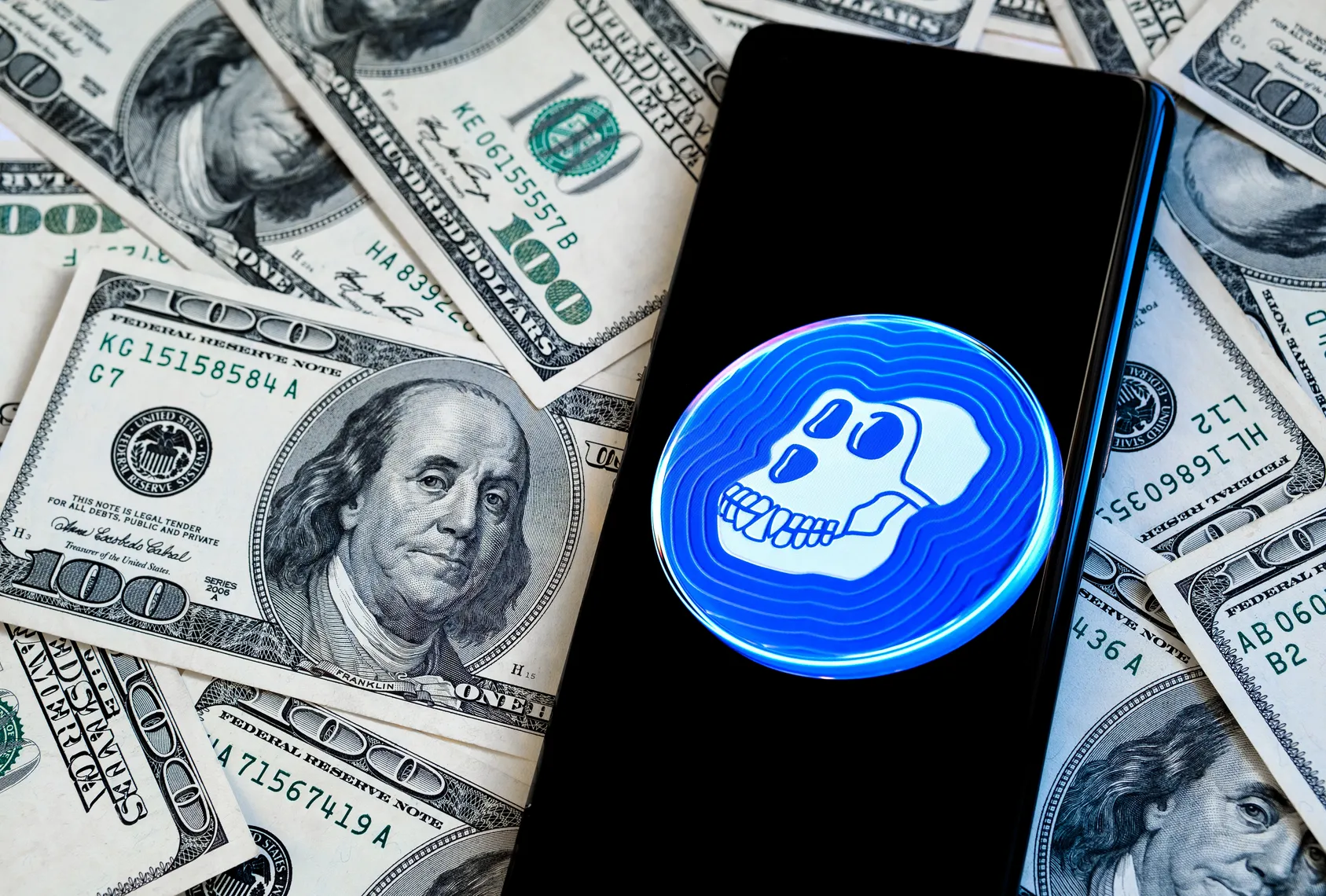 Apecoin (APE) price prediction Apecoin logo on a smartphone screen with piles of US dollars in the background