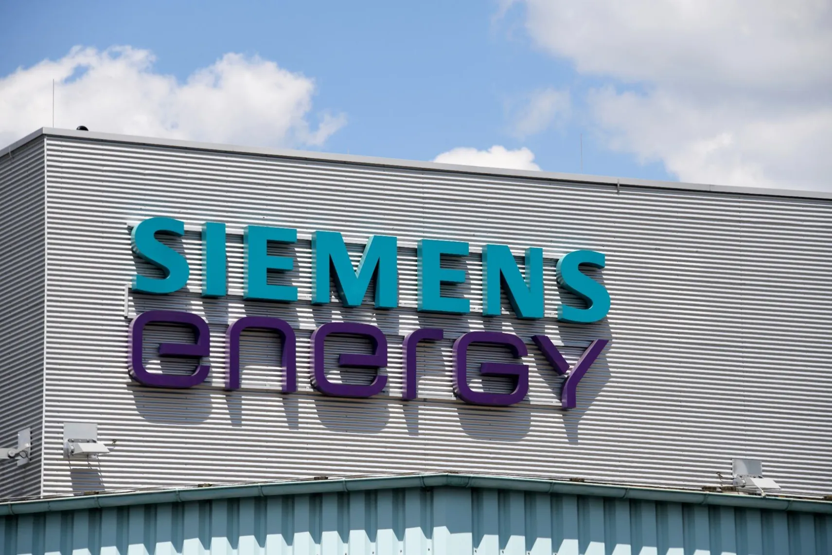 Siemens Energy logo displayed on the exterior of an industrial building against a blue sky Siemens Energy logo displayed on the exterior of an industrial building against a blue sky