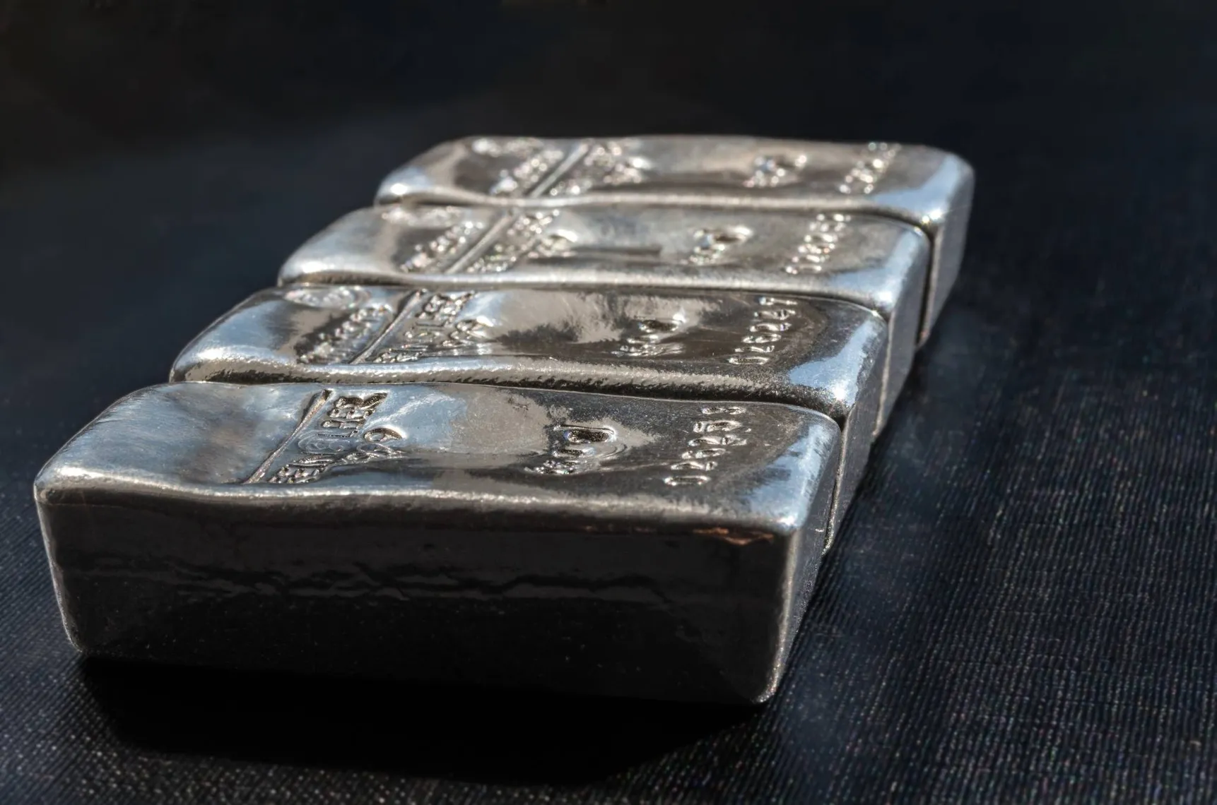 Stack of silver bullion bars arranged on a dark surface Stack of silver bullion bars arranged on a dark surface