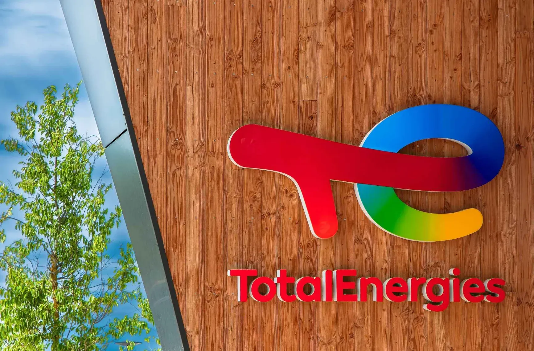 Logo TotalEnergies monté sur un mur en bois à l'extérieur d'un bâtiment