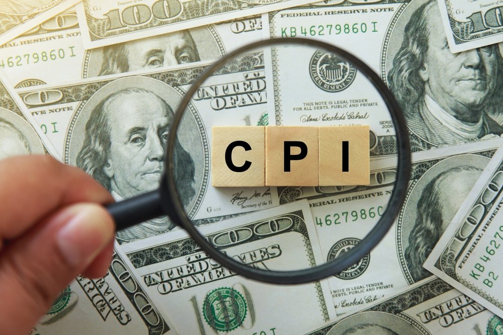 hand holding magnifying glass investigating wooden block with words CPI, consumer price index on dollar bills.