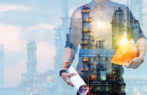 engineer in a protective helmet with a background of an oil refining plant