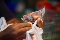 A customer handles cash at a market in the U.K. A customer handles cash at a market in the U.K.