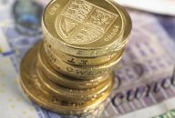 British banknotes and coins photographed directly above. The coins are in a stack, placed on top of the banknotes. British banknotes and coins photographed directly above. The coins are in a stack, placed on top of the banknotes.