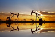 Oil price forecast Oil wells pictured in an oil field, silhouetted against clouds