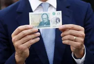 Suited businessman holding a five pound note