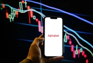 Smartphone displaying the Alphabet logo in front of a bearish candlestick stock chart, representing the technology company and its stock market performance.