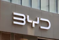 BYD-Logo an einer modernen Gebäudefassade mit Glasfenstern darüber montiert