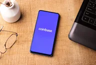 Application Coinbase affichée sur un smartphone posé sur un bureau