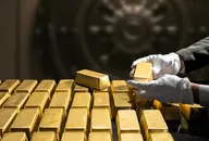 Lingotti d’oro disposti in file ordinate davanti a una cassaforte