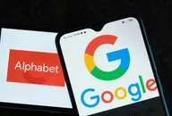 Ein Smartphone zeigt das Google-Logo vor einem Bildschirm mit dem Alphabet-Unternehmenslogo