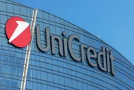 UniCredit logo displayed on the glass facade of a modern office building against a clear blue sky
