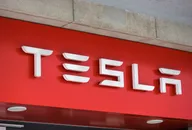 Tesla-Logo auf einem roten Ladenschild an einer Gebäudefassade