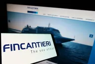 Smartphone che mostra il logo Fincantieri con un'immagine sfocata di una nave da crociera su un sito web sullo sfondo