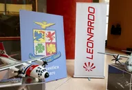 Modello di aereo esposto all'interno accanto a un banner dell'azienda Leonardo e uno stemma araldico, che mostrano il branding aeronautico e della difesa