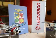 Esposizione dell'azienda aerospaziale Leonardo con modelli di aeromobili, branding e materiali espositivi, che rappresentano l'industria della difesa e dell'aviazione