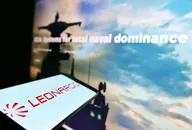 Smartphone che mostra il logo dell'azienda Leonardo con sfondo sfocato a tema difesa sullo schermo