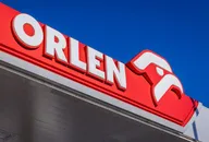 Orlen logo displayed on a fuel station canopy against a clear blue sky
