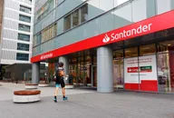 Exterior of a Santander bank branch displaying the company logo on a modern office building, representing the international banking and financial services group. 