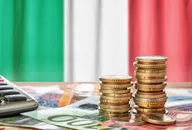 Stacks of euro coins on banknotes with the Italian flag in the background.