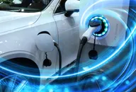 Electric vehicle at charging station with the power cable supply plugged in owith