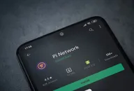 Pi Network app play store page on the display of a black mobile smartphone on dark marble stone background. Top view flat lay with copy space.