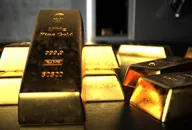 Fine gold bars in front of an open safe.