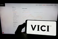 Person holding cellphone with logo of US real estate company Vici Properties Inc. on screen in front of business webpage. Focus on phone display